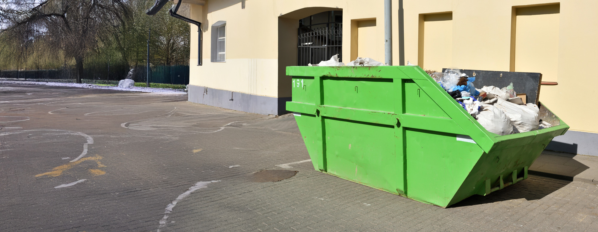 Grüner Container vor einem Gebäude.